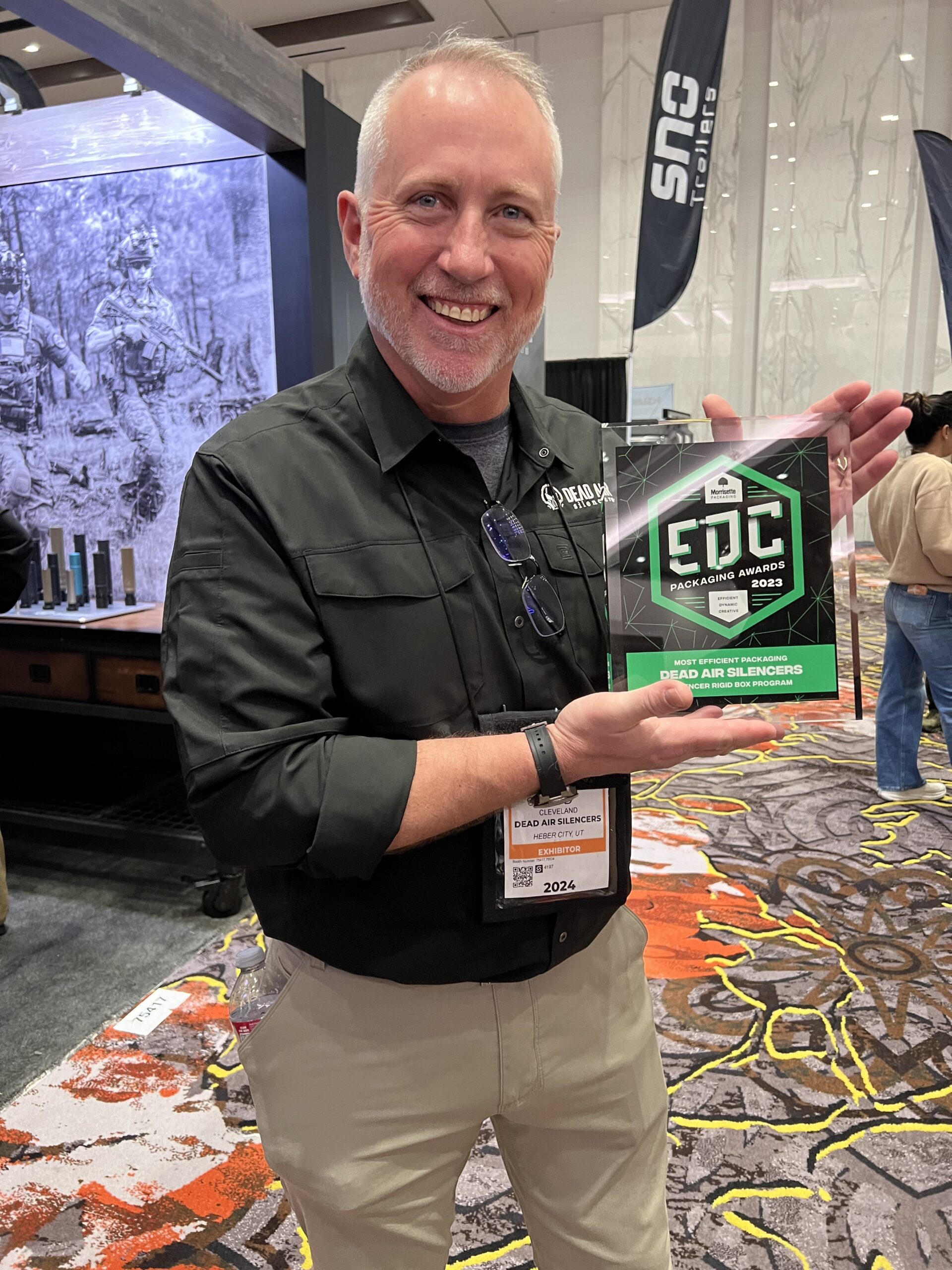 Dead Air Silencers employee holds award plaque for the EDC Packaging Awards.